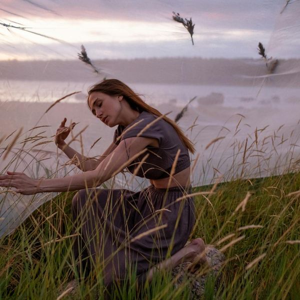 Calm person sitting in a meditative pose in a serene setting.